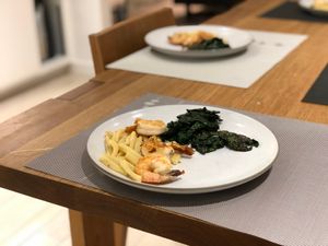 two plates of pasta with shrimp and kale