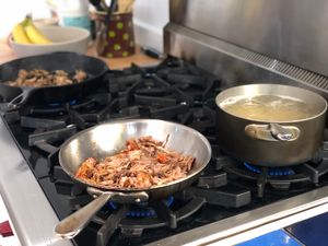 Mushrooms, pulled pork, and pasta cooking separately on a stovetop