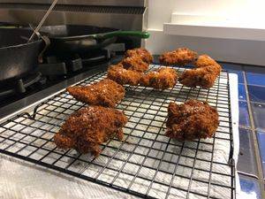 a few pieces of fried chicken on a cooling rack