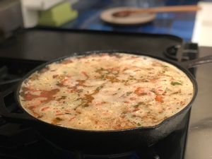 A cast iron skillet cooking, filled to the brim