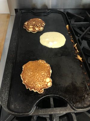 3 pancakes cooking on a griddle
