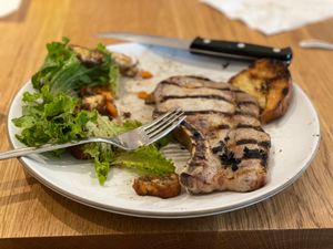 Pork chop with green salad and grilled bread