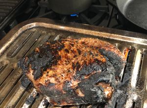 a large burned steak on a broiling pan