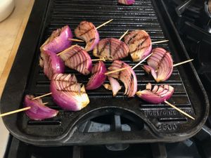 red onion slices cooking on a grill pan