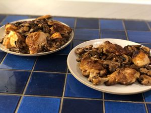 Two plates with cooked chicken and mushrooms