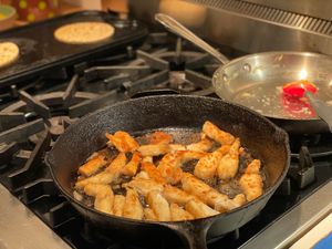 Fish frying while tortillas warm up in the background