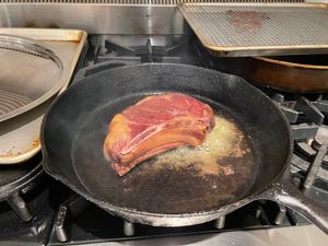 Ribeye cooking in a cast-iron pan