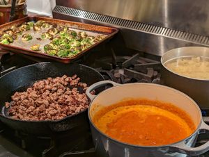 Pasta, sauce and brussels sprouts on a stovetop